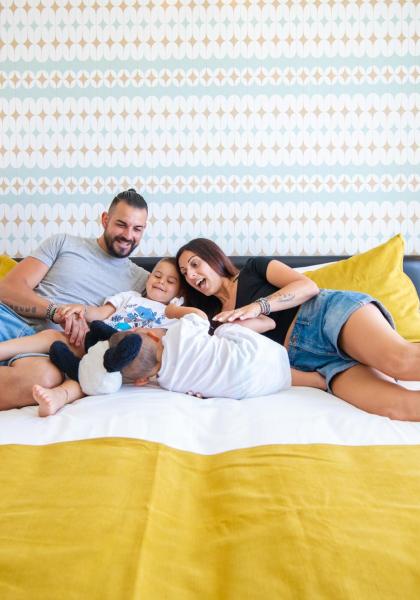 Famiglia felice gioca sul letto in una stanza luminosa.