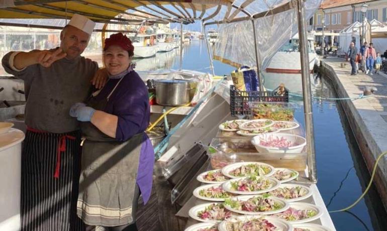 Cuisiniers sur un bateau avec des salades près du canal.