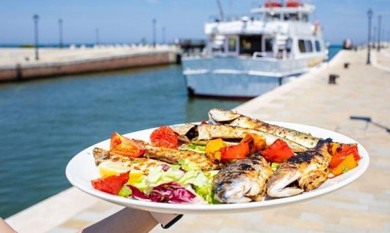 Poisson grillé avec légumes sur une assiette près de la mer.