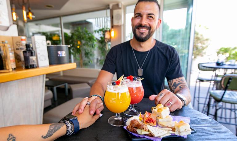 Uomo sorridente con cocktail e snack, mano nella mano.