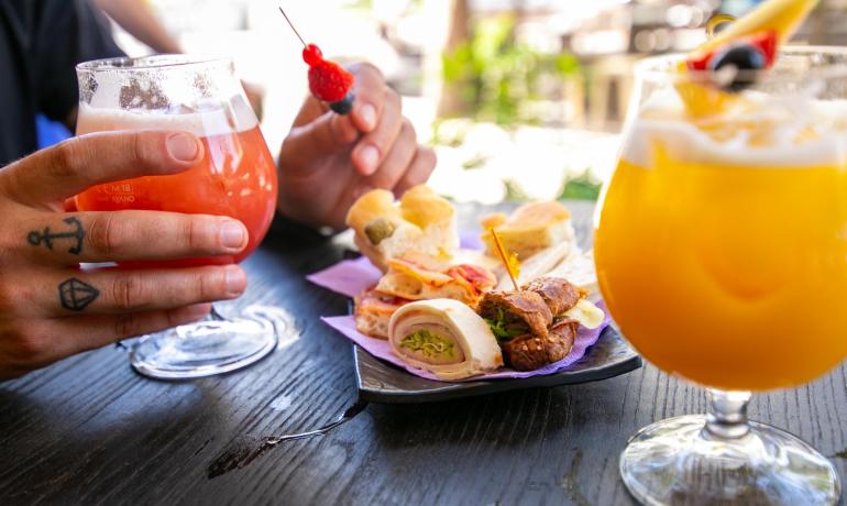 Cocktails and snacks on an outdoor table, relaxing atmosphere.